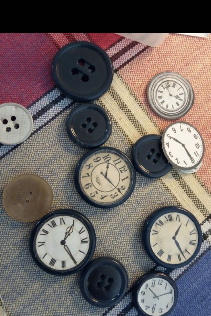 there are many different clocks on the table and one is made out of buttons with holes in them