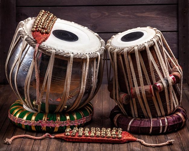 two large drums sitting next to each other on a wooden floor with beaded trim