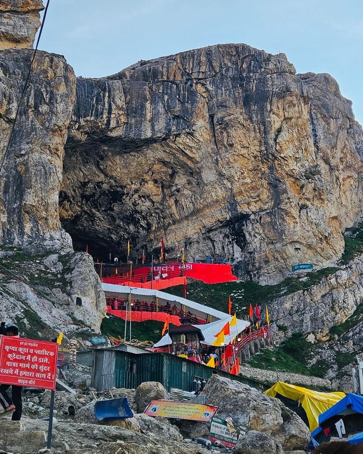 there are many tents set up in front of the mountain side with flags on them