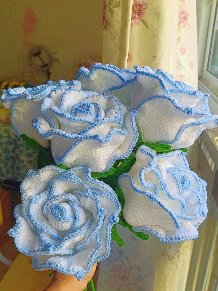 there are three white roses in the vase on the window sill, and one is blue