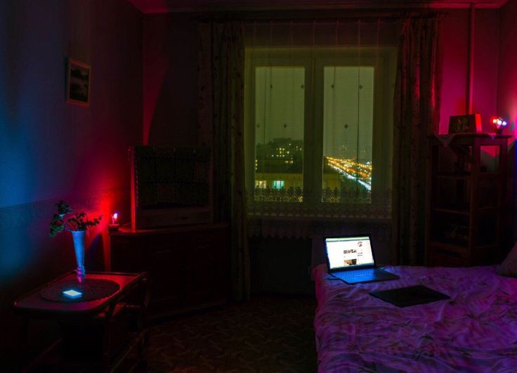 a laptop computer sitting on top of a bed in a room with red and blue lights