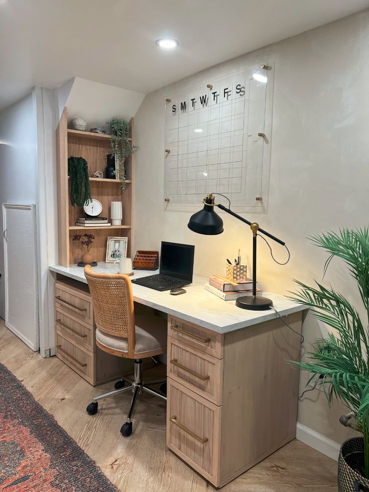 a desk with a laptop computer on top of it next to a potted plant