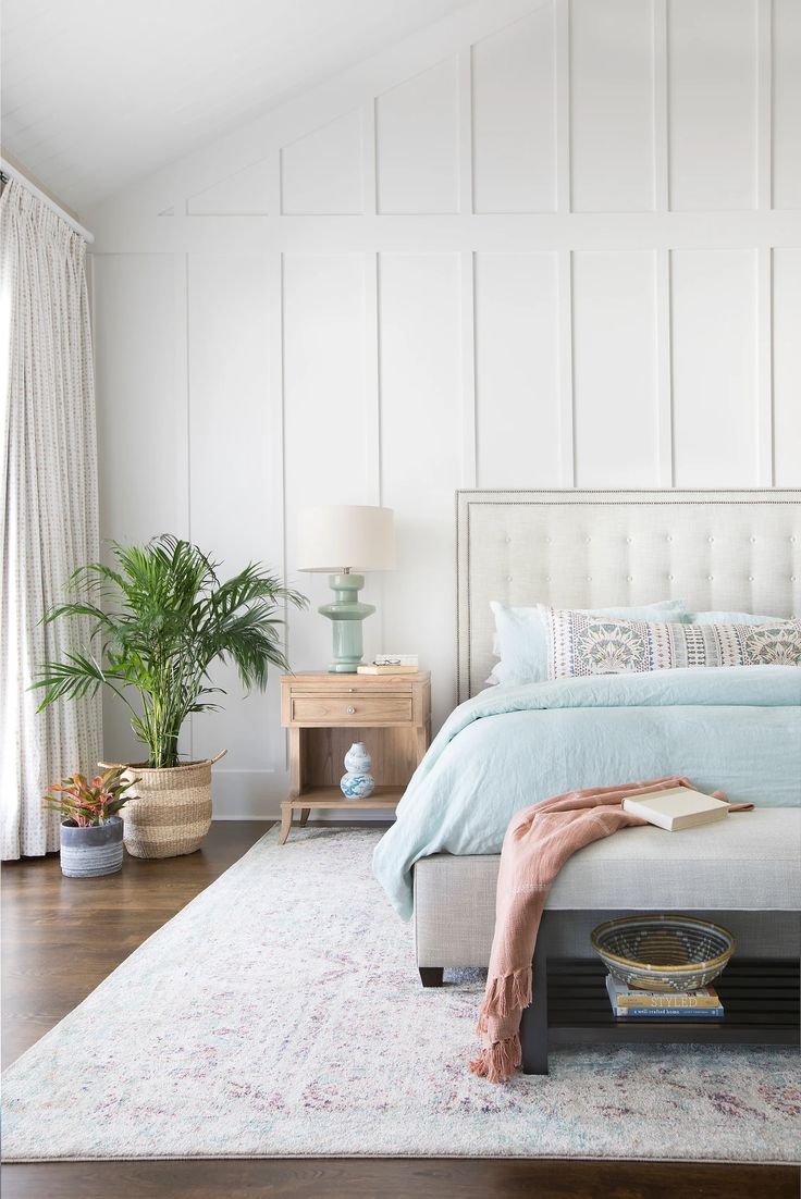 a bedroom with a bed, nightstands and plants on the side table in front of it