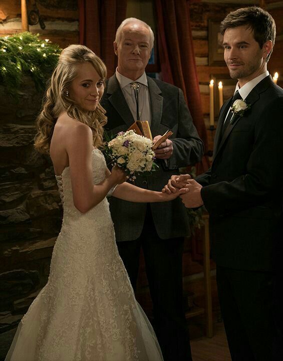 a man and woman standing next to each other in front of a candle lit room