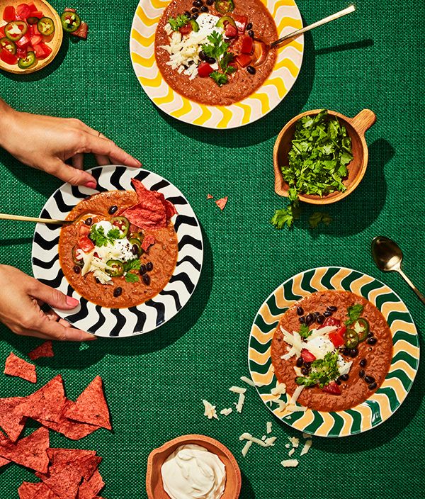 several plates of food on a green tablecloth with tortillas, salsa and guacamole