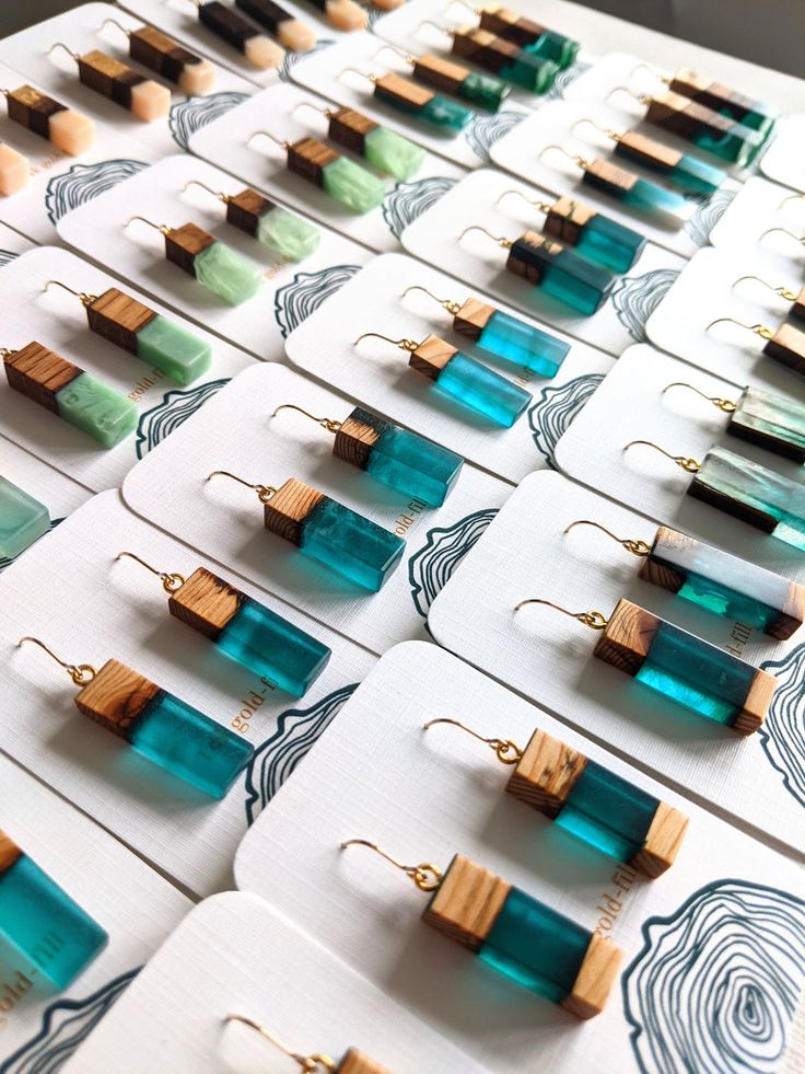 many different types of wooden earrings are displayed on a white table with blue and green designs