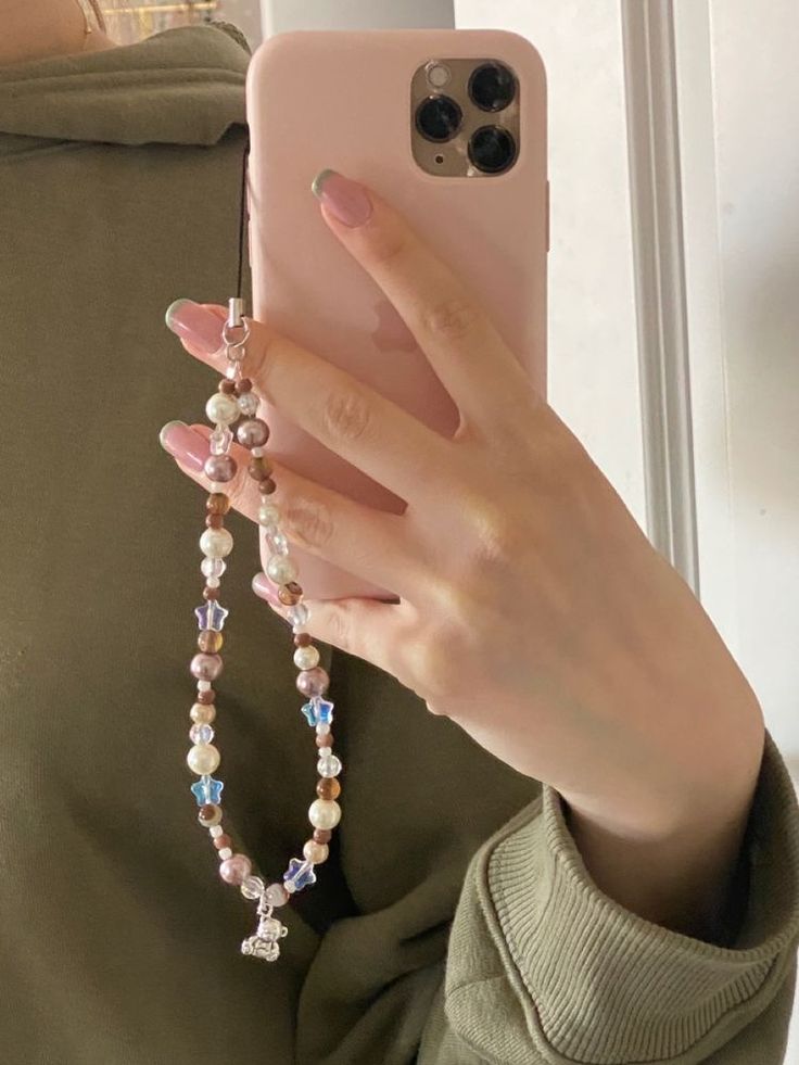 a woman is holding her phone up to the camera and wearing a necklace with beads on it