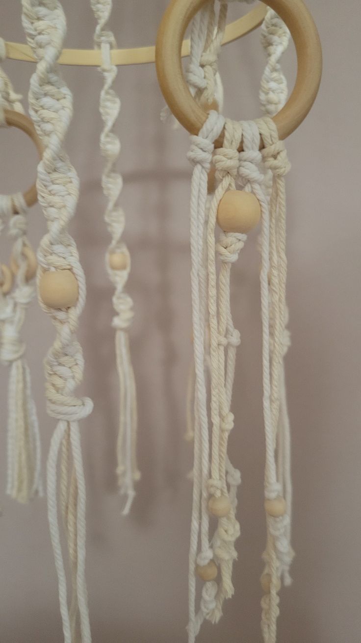 a close up of a mobile made out of rope and wood circles with wooden beads hanging from it