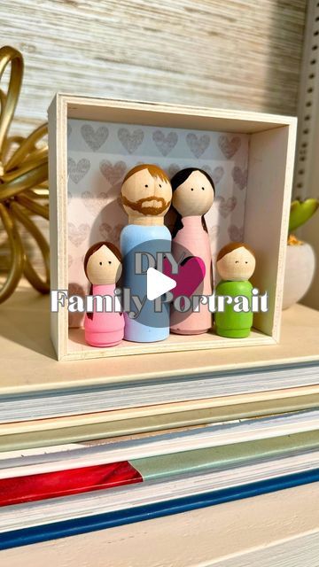 a wooden box with three small figurines in it on top of some books