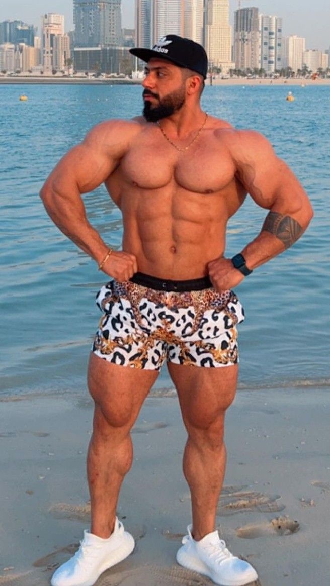 a man standing on top of a beach next to the ocean wearing leopard print shorts