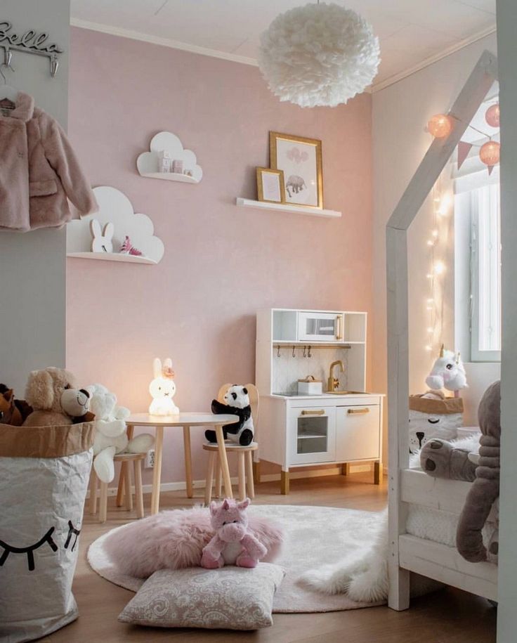 a child's bedroom with pink walls and white furniture