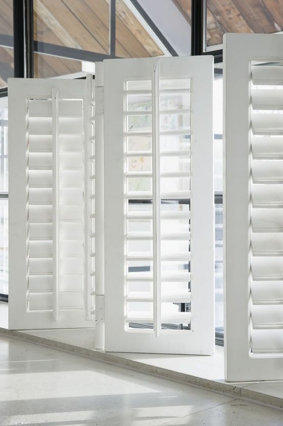 two open white shutters in an empty room