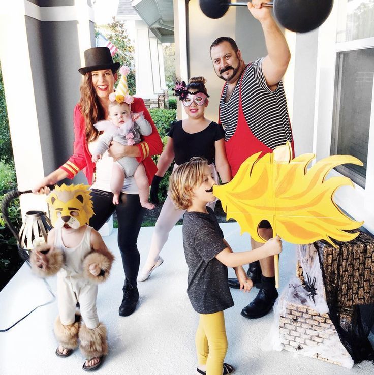 a group of people that are standing in front of a house with balloons and costumes