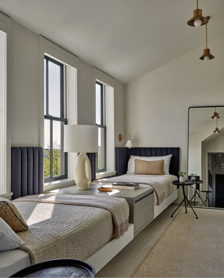 a bedroom with two twin beds in front of three large windows and a rug on the floor