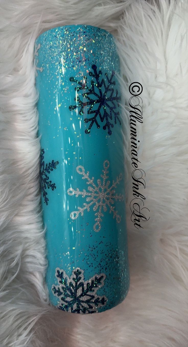 a blue cup with snowflakes on it sitting on a white fur covered surface