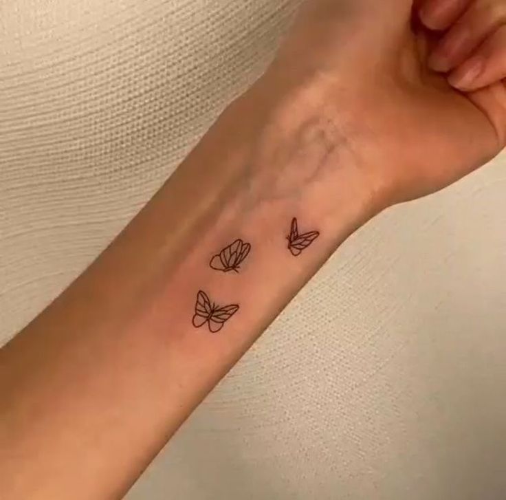 a woman's arm with three butterflies tattoo on the left side of her wrist