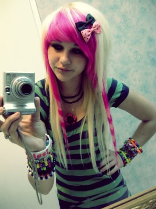 a woman with pink hair taking a selfie in front of a mirror holding a camera