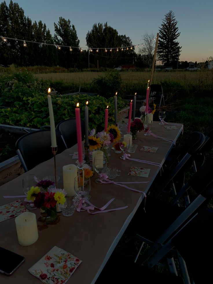 a long table is set up with candles and flowers for an outdoor dinner or party