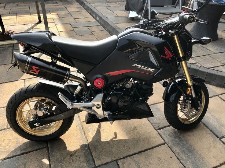 a black motorcycle parked on top of a sidewalk