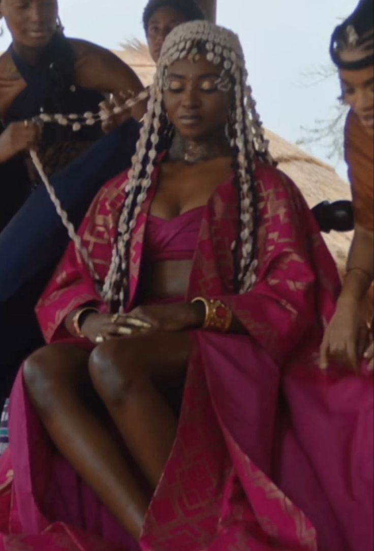 a woman in a pink dress sitting next to other people