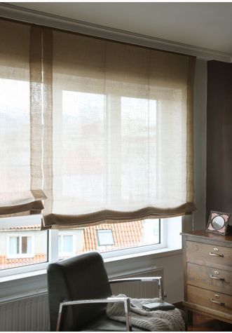 a chair sitting in front of a window next to a dresser with drawers on it