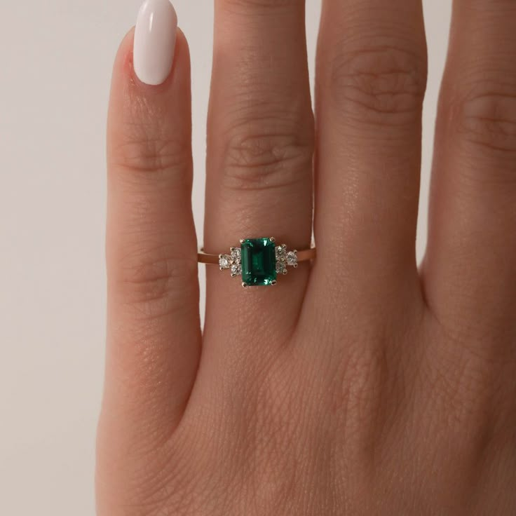 a woman's hand with a ring on it and an emerald stone in the middle