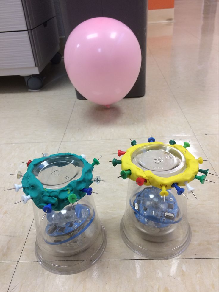 two plastic toys sitting on top of a floor next to a pink ball and balloon