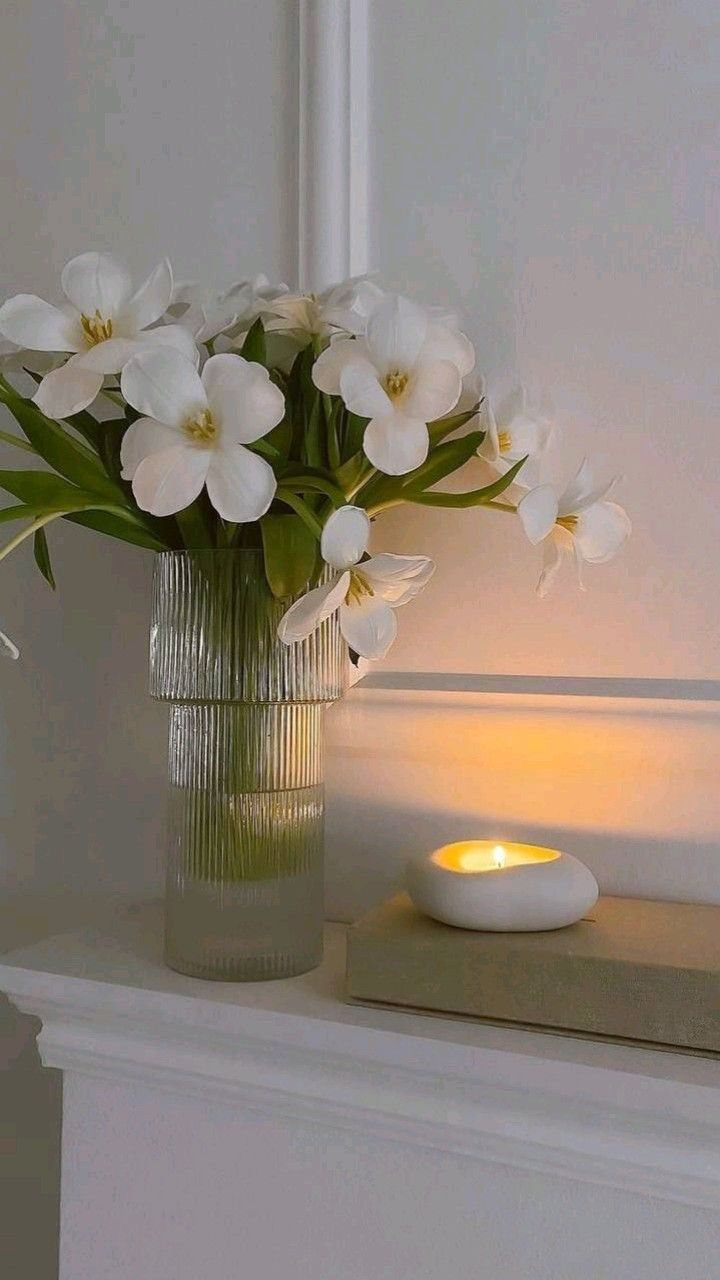 a vase filled with white flowers next to a lit candle