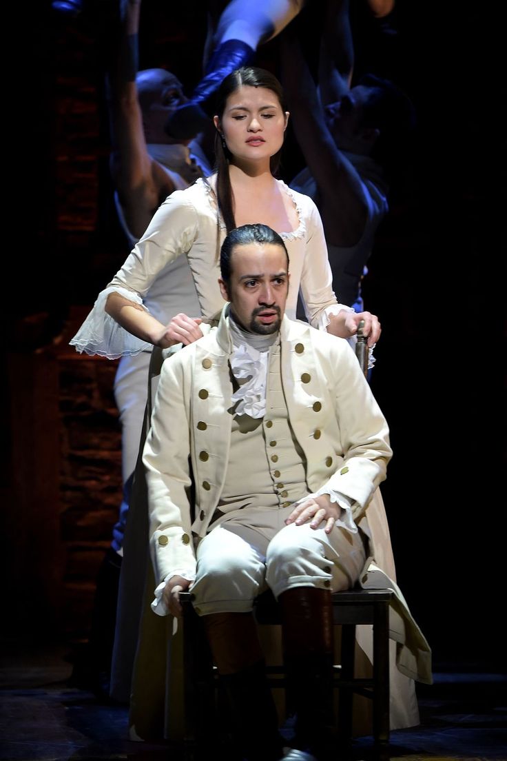 a man sitting on top of a chair next to a woman in a white dress