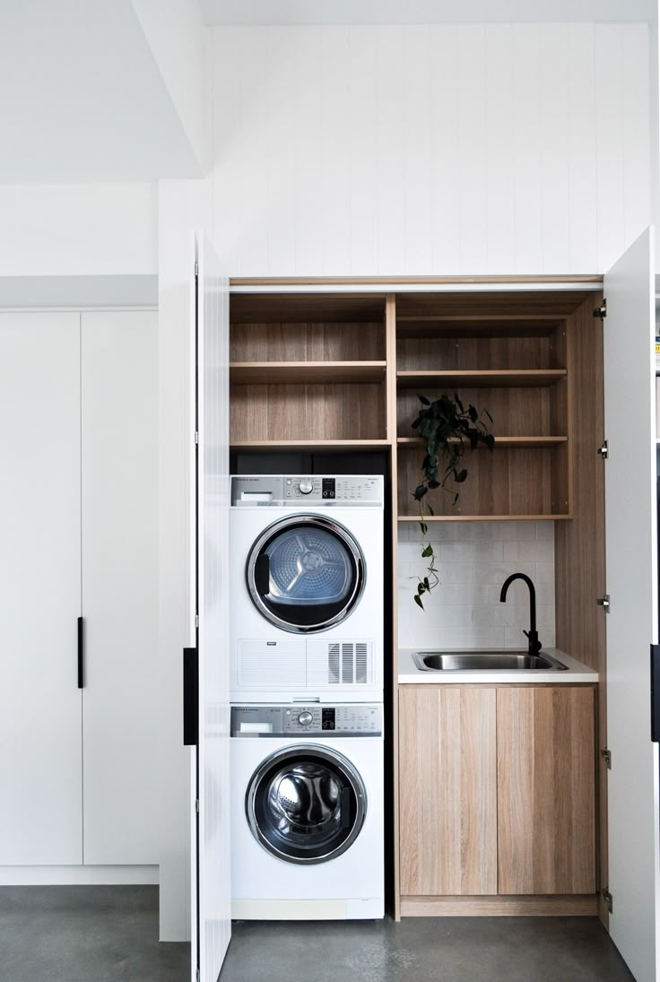 a washer and dryer in a room with open shelves on the wall next to each other