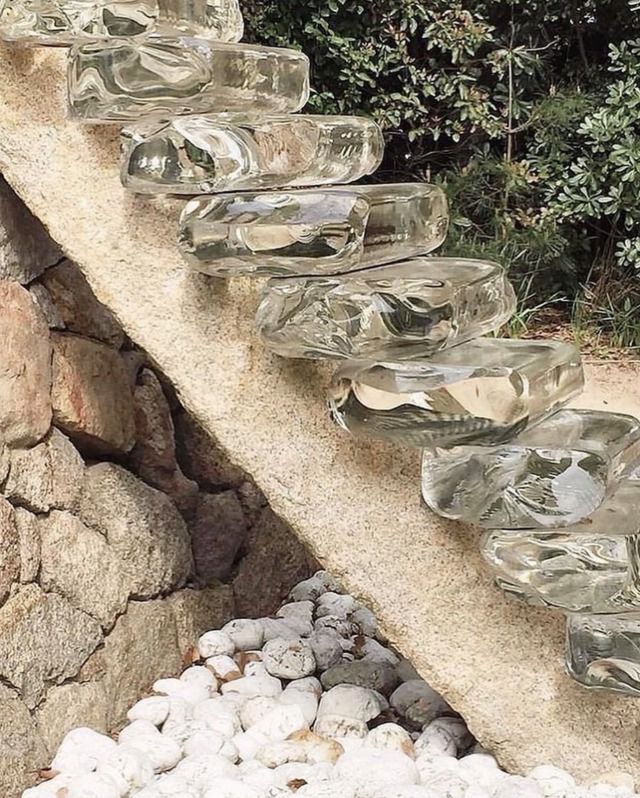 a bunch of glass bowls sitting on top of a stone wall next to some rocks