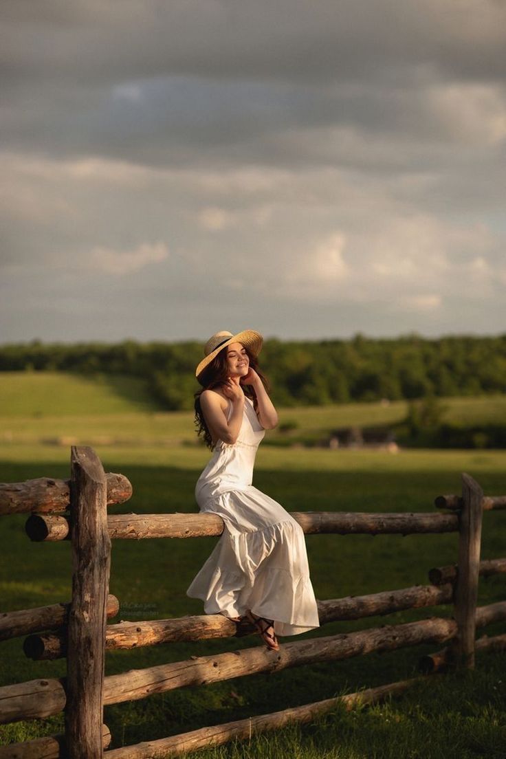 a woman in a white dress leaning on a fence