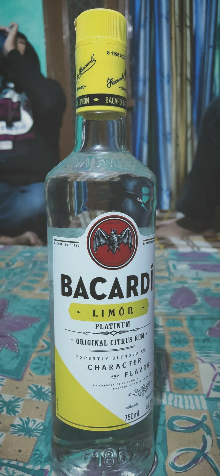 a bottle of bacardi liquor sitting on top of a blue tablecloth covered floor