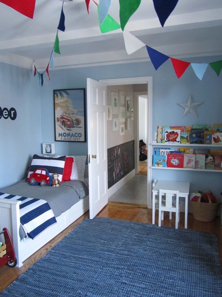 a bedroom with blue walls and colorful flags hanging from the ceiling