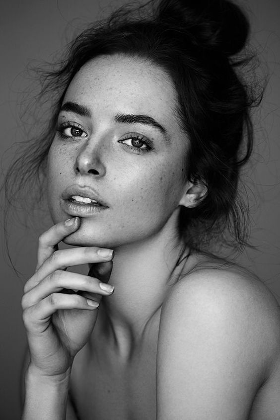 a black and white photo of a woman with freckles on her face looking at the camera