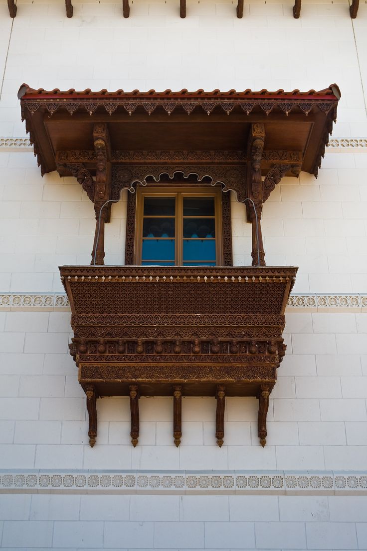 an ornate balcony on the side of a white building with wooden balconies and windows