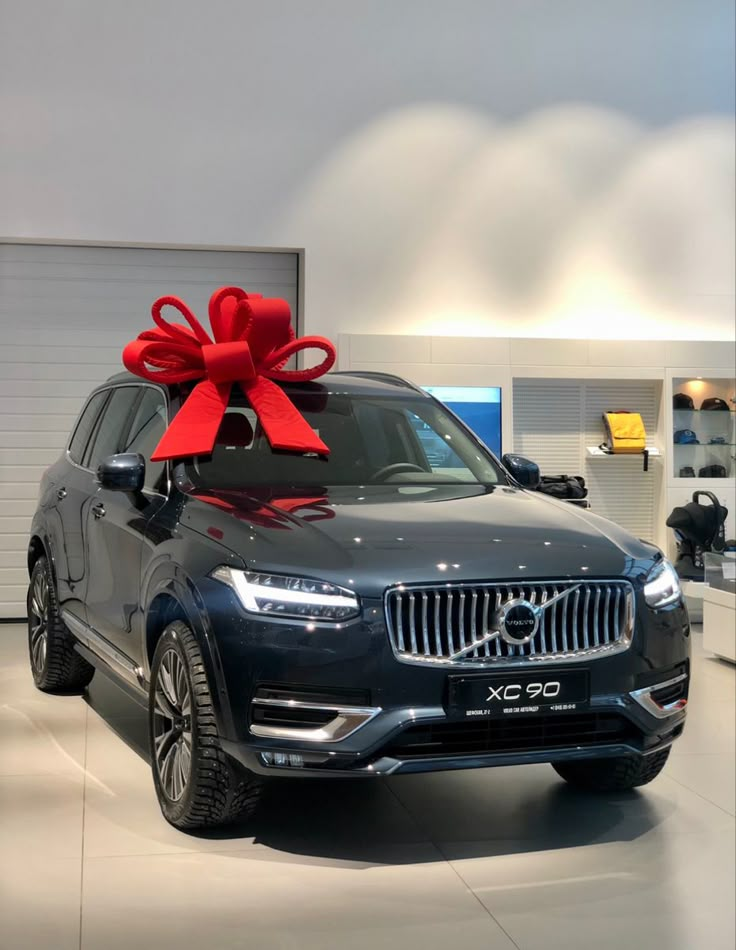 a car with a large red bow on it's hood in a showroom