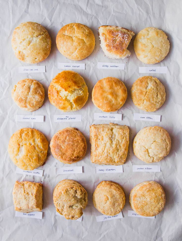 a table topped with lots of different types of breads and muffins next to each other