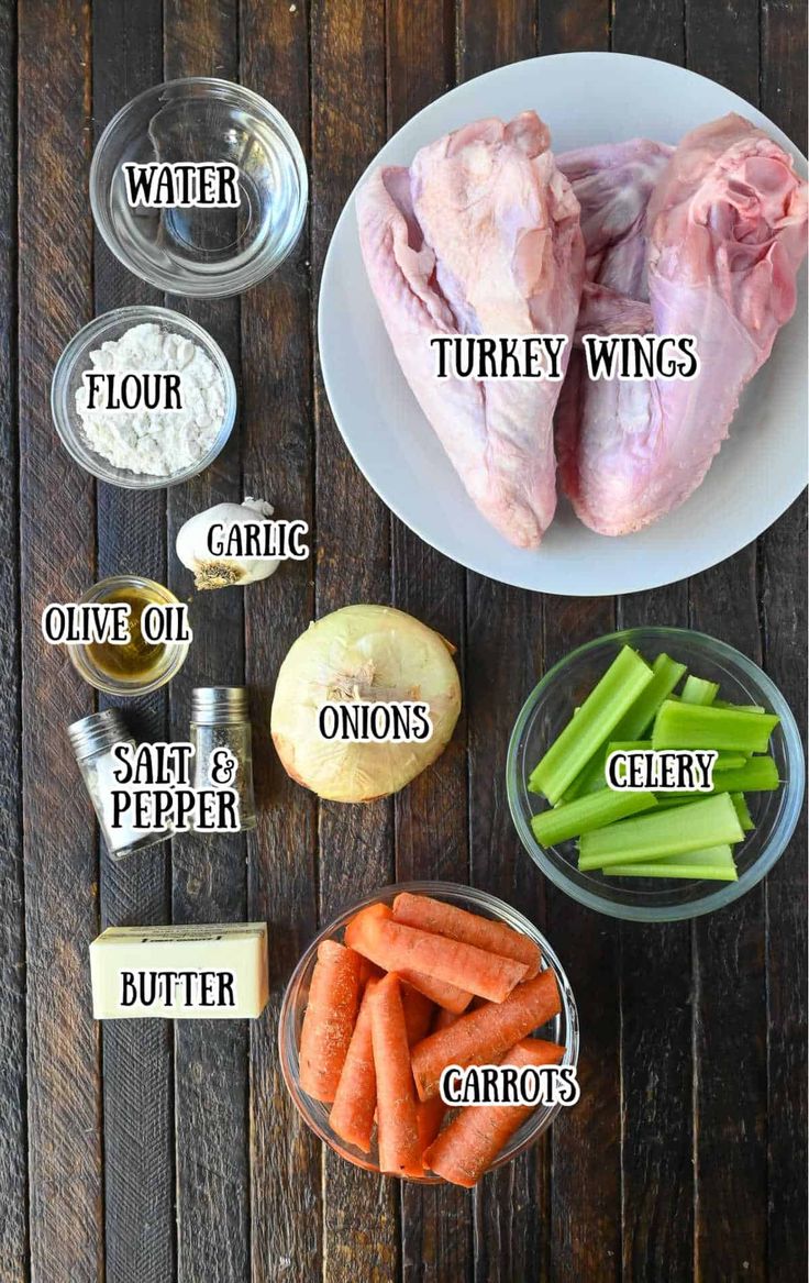 ingredients to make chicken wings on a wooden table including carrots, celery and onions