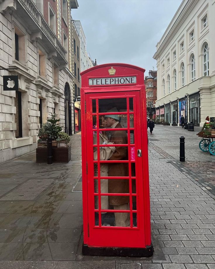 a red phone booth sitting on the side of a street