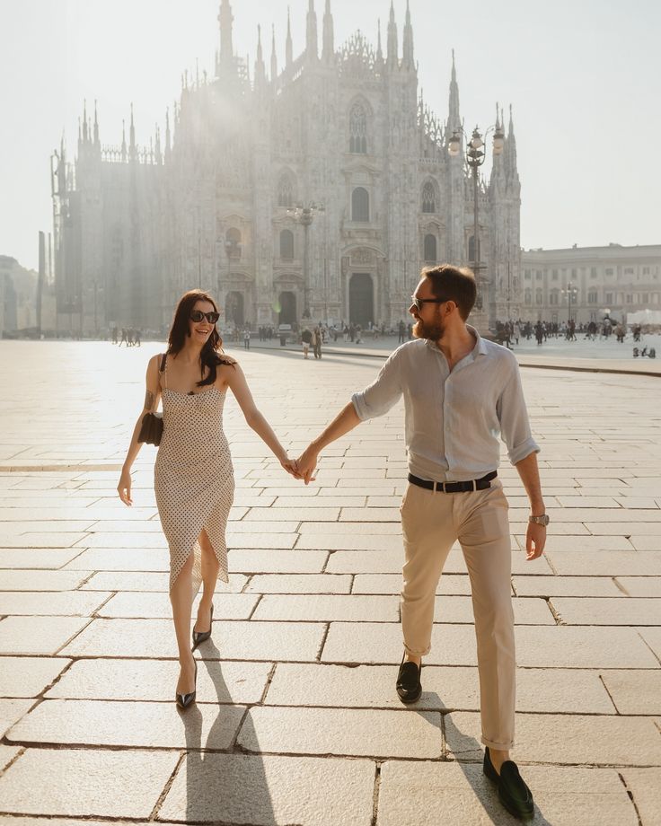 a man and woman holding hands in front of a castle