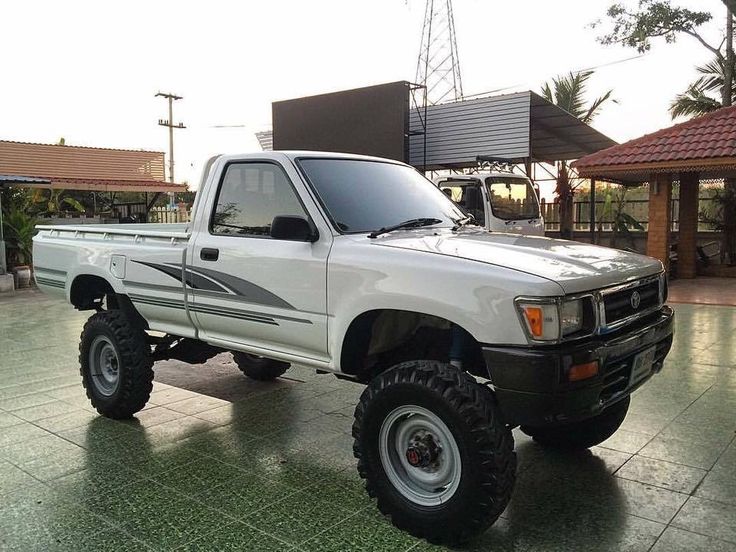 a white pick up truck parked on top of a tile covered floor next to a building