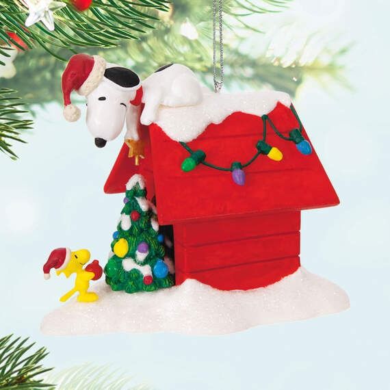 a christmas ornament hanging from a tree with a dog in it's house