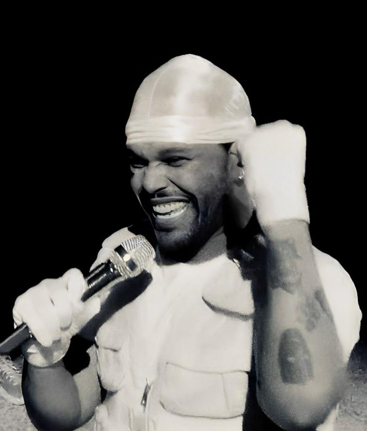 a black and white photo of a man wearing a helmet holding a microphone in his right hand