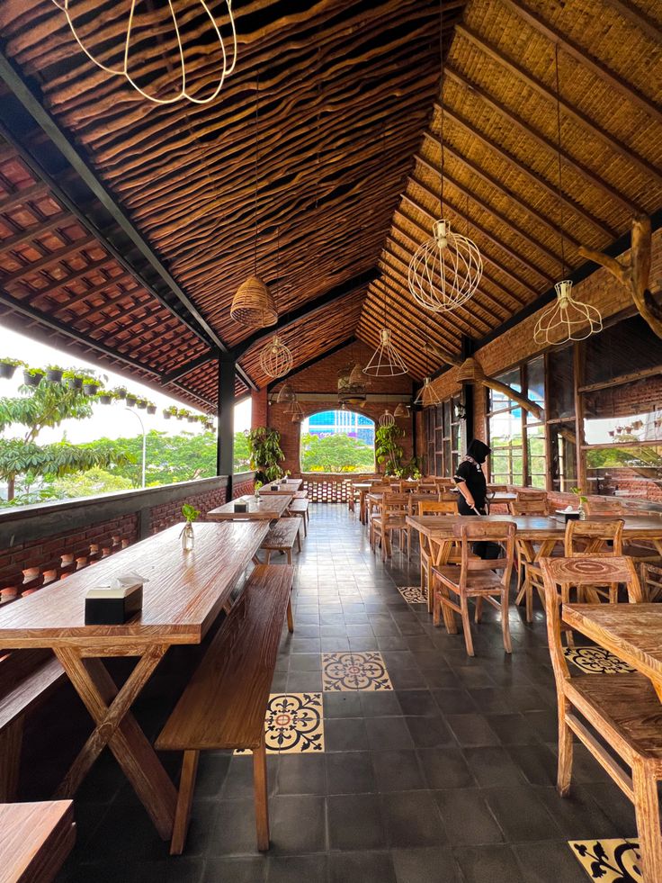 the inside of a restaurant with tables, benches and lamps hanging from the roof above