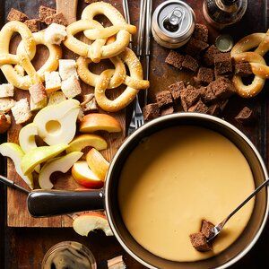 apples, pretzels and other snacks on a cutting board next to an apple cider