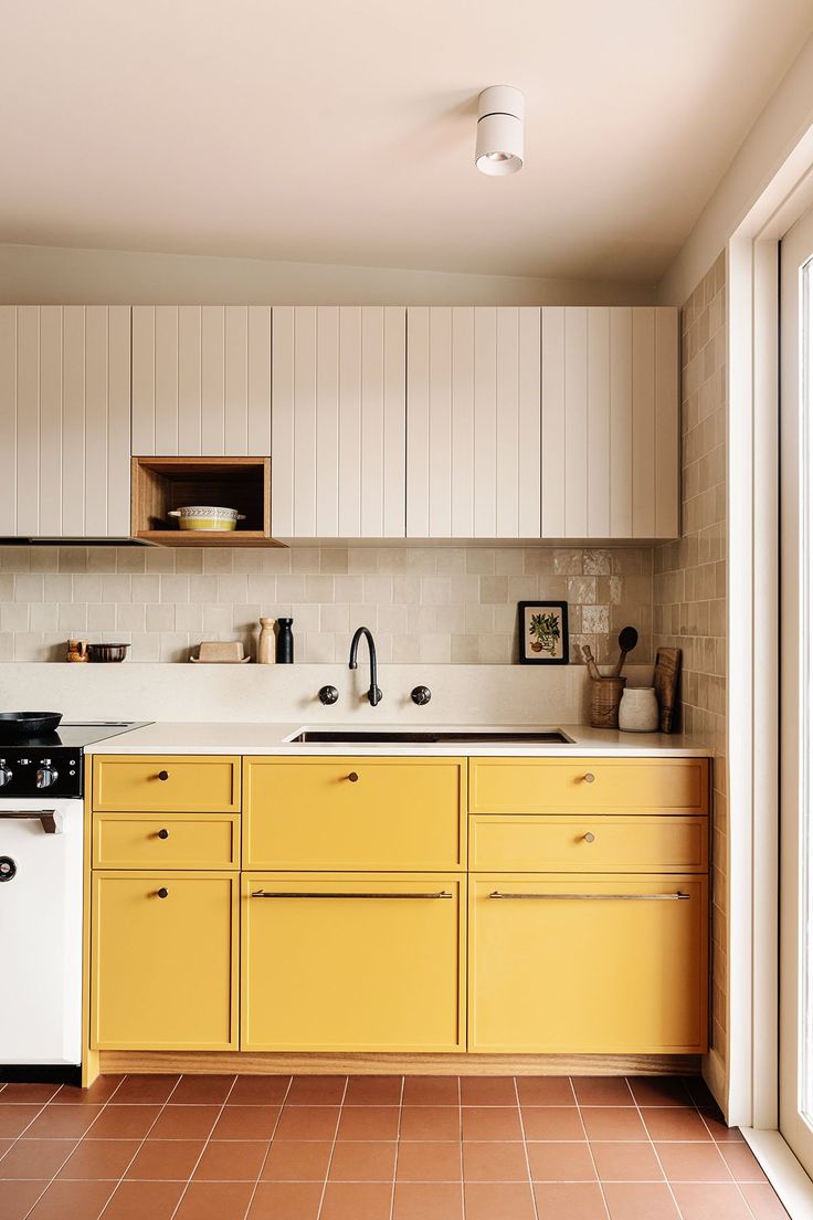 a kitchen with yellow cabinets and white appliances