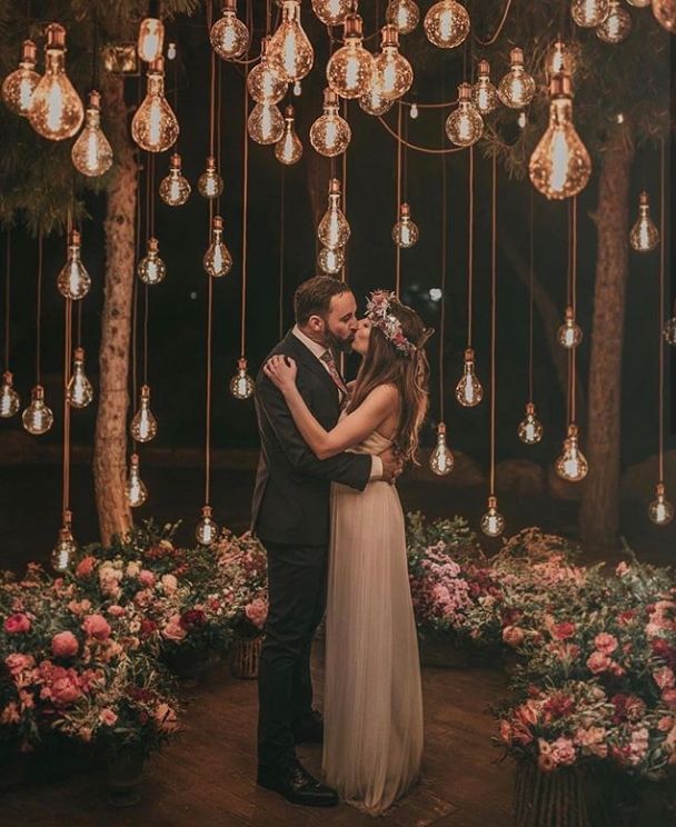 a bride and groom standing in front of chandelier with lights hanging from the ceiling