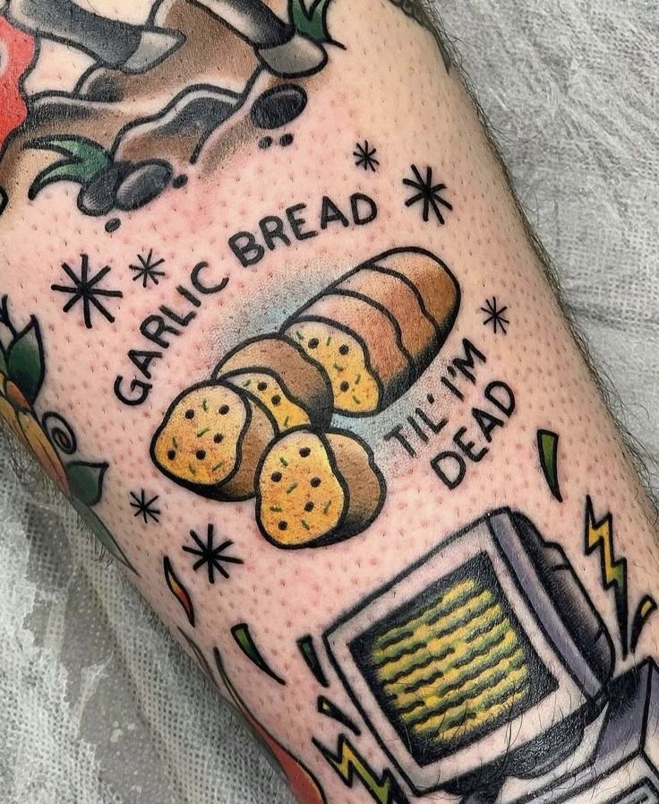 a close up of a person's leg with tattoos on it and some bread