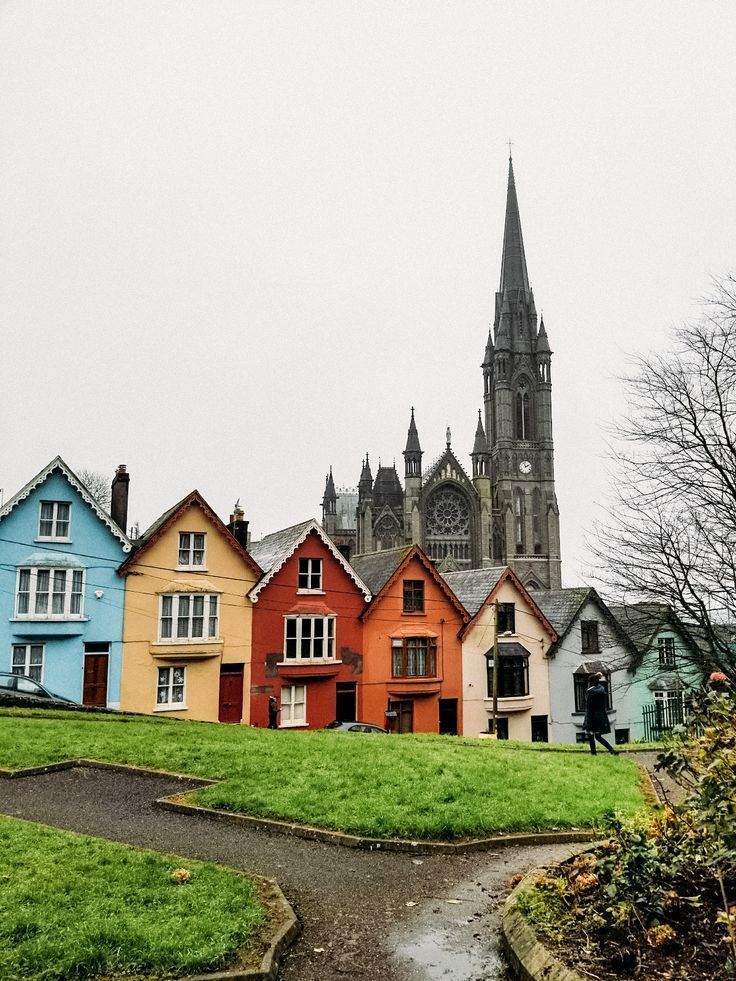 a row of colorful houses with a church in the backgrouund and green grass